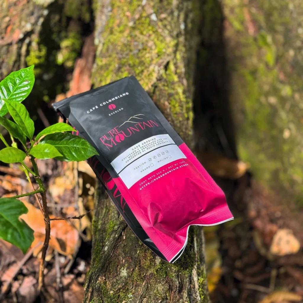Bolsa de café Pure Mountain sobre un tronco en un entorno natural, destacando el origen auténtico y sostenible del café colombiano.